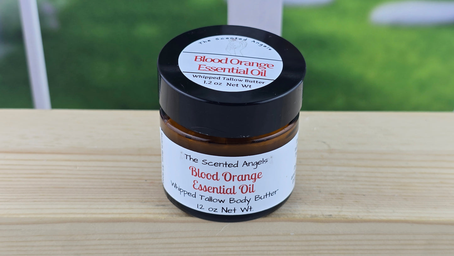 Jar of blood orange essential oil whipped tallow body butter on a wooden surface.
