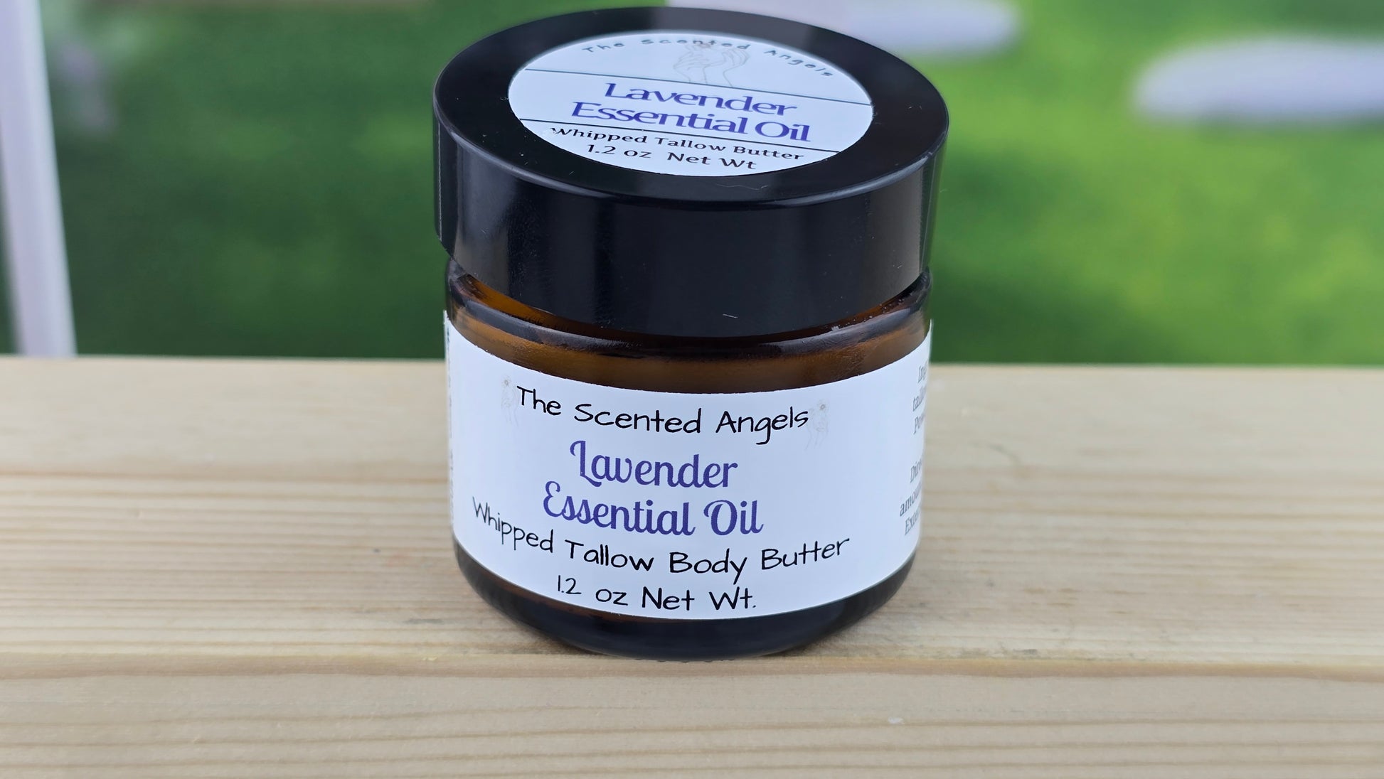 Jar of lavender essential oil whipped tallow body butter on a wooden surface.