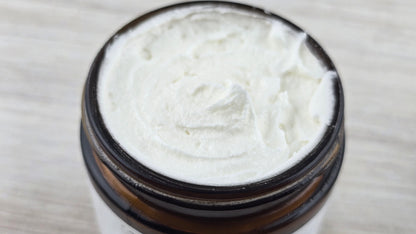 Close-up of a jar with white cream on a light wooden surface.