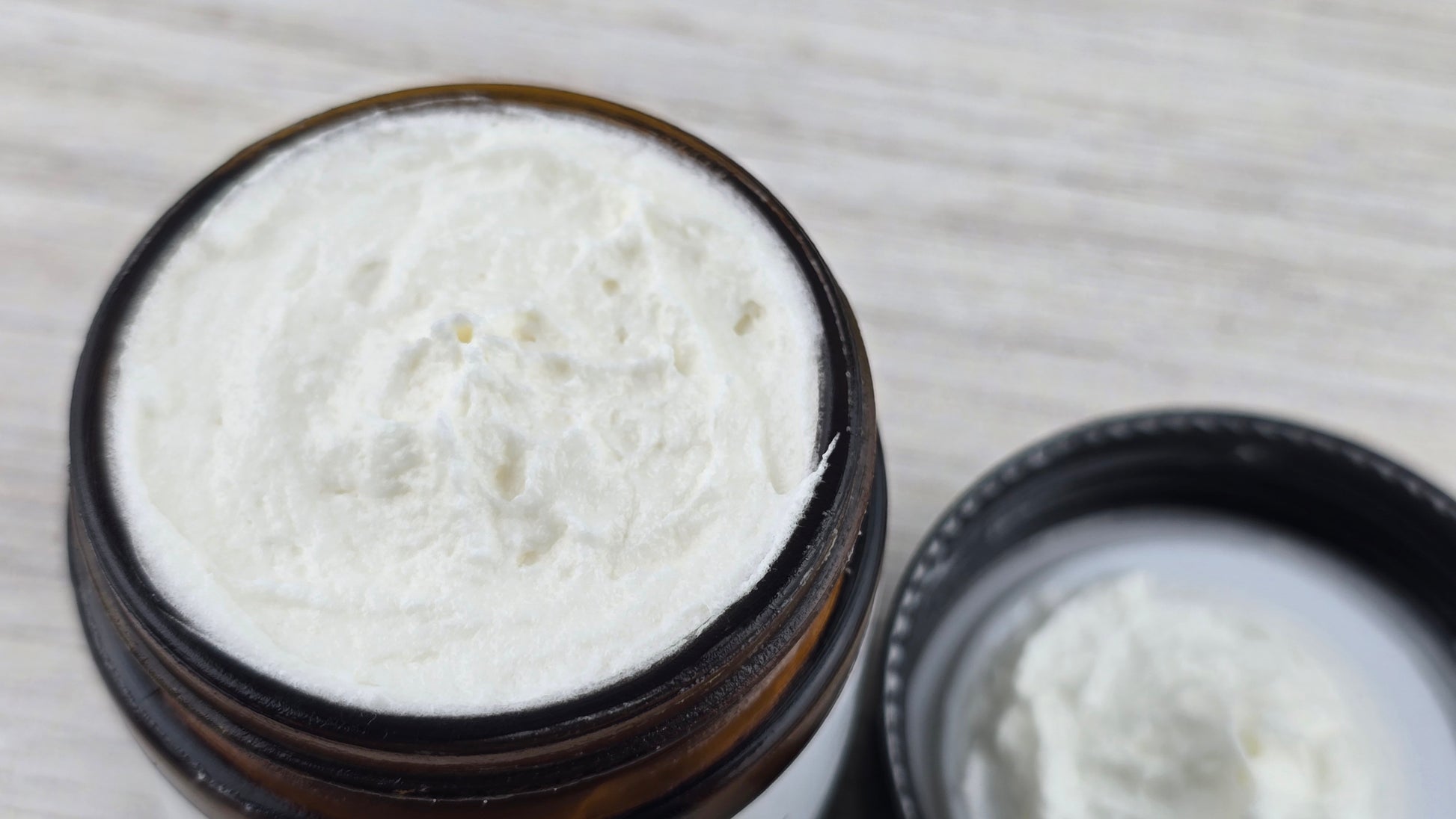 Open jar of white cream on a wooden surface