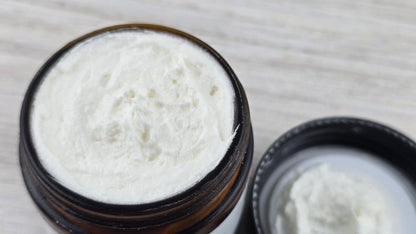 Open jar of white cream on a wooden surface