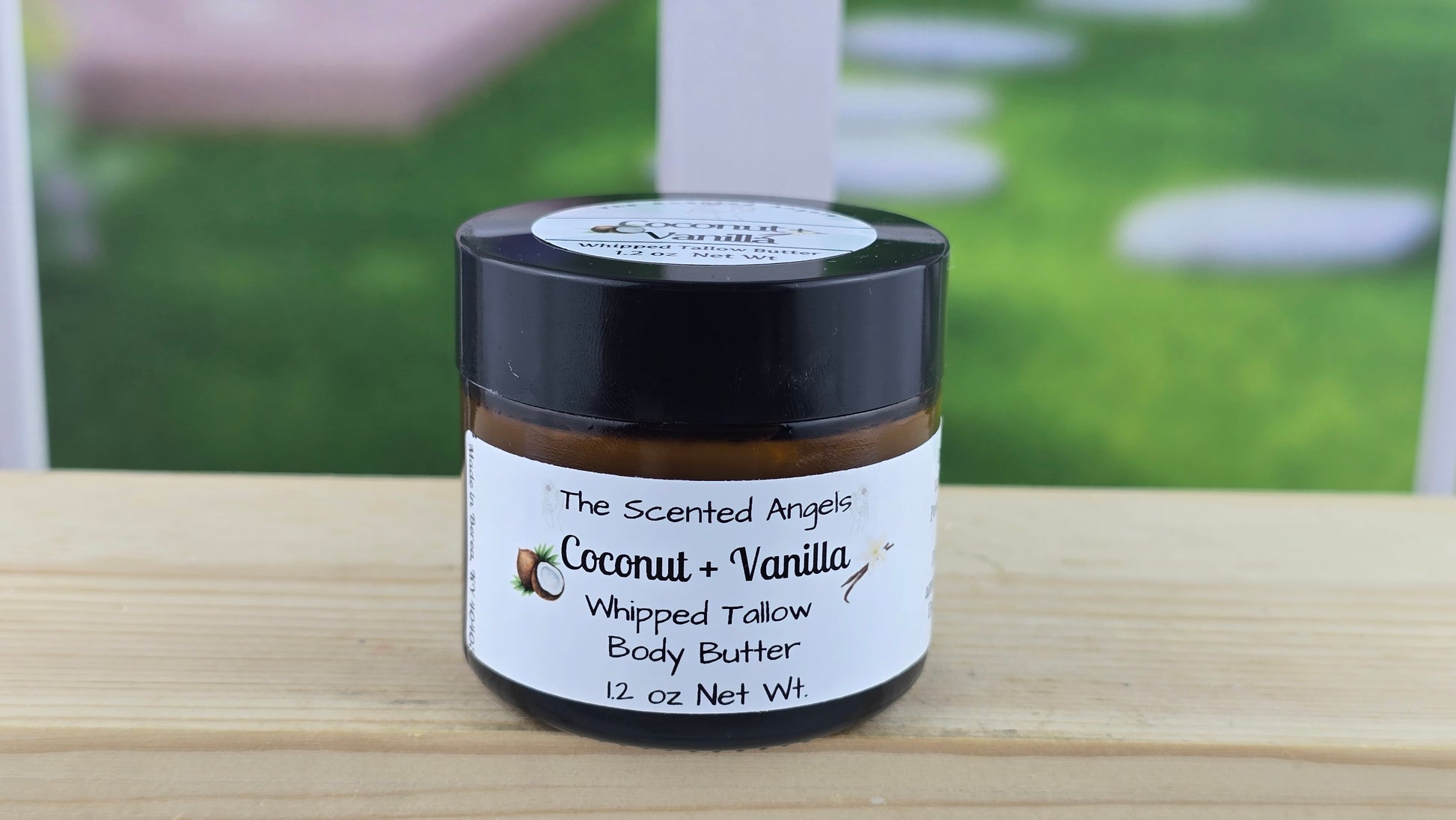 Jar of coconut and vanilla whipped tallow body butter on a wooden surface.