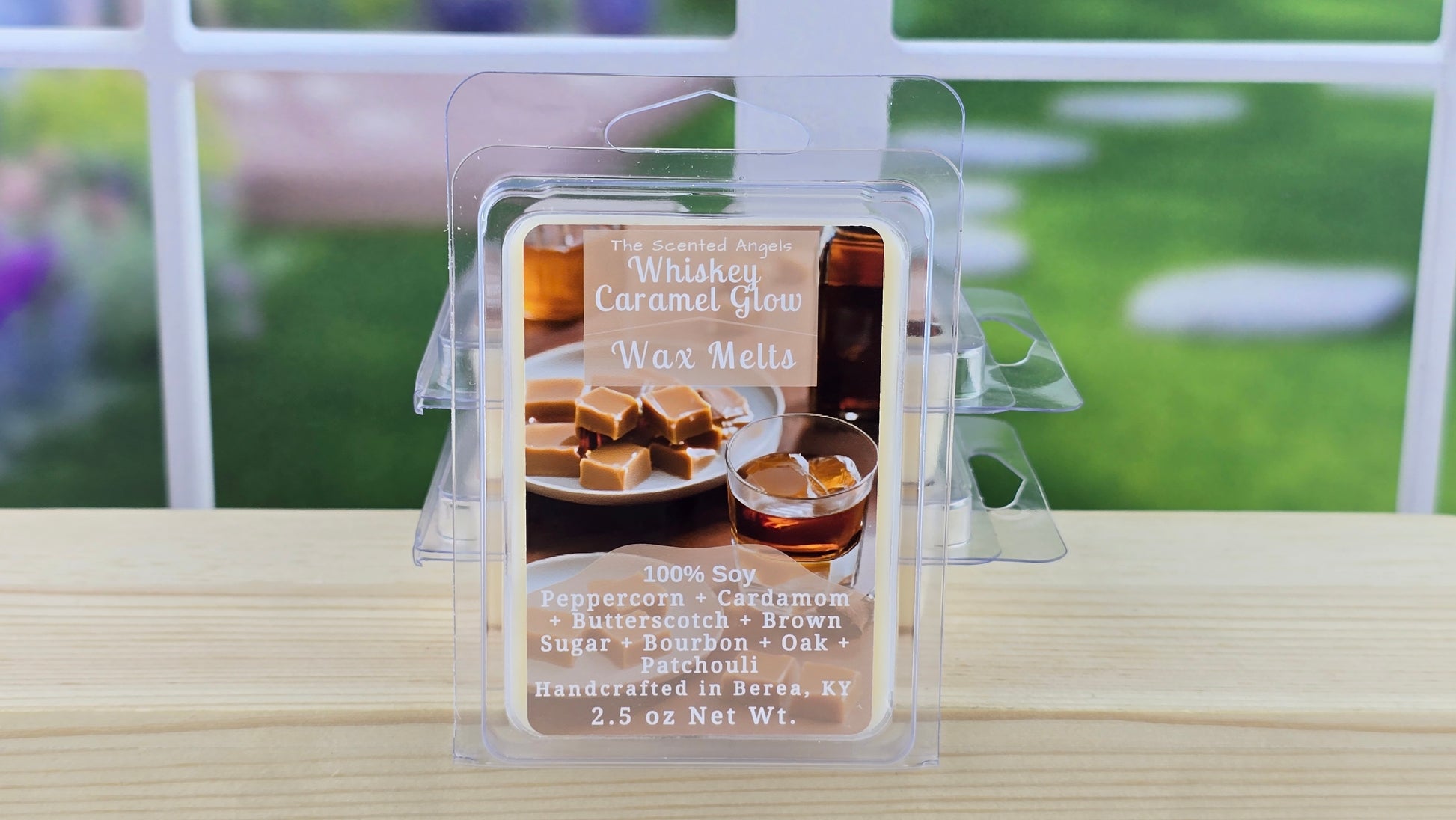Whiskey Caramel Glow wax melts packaging on a wooden surface with a blurred outdoor background